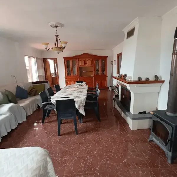 Salón para reuniones Sala de estar amplia con mesa, sillas, sofá y chimenea, decorada en tonos neutros.